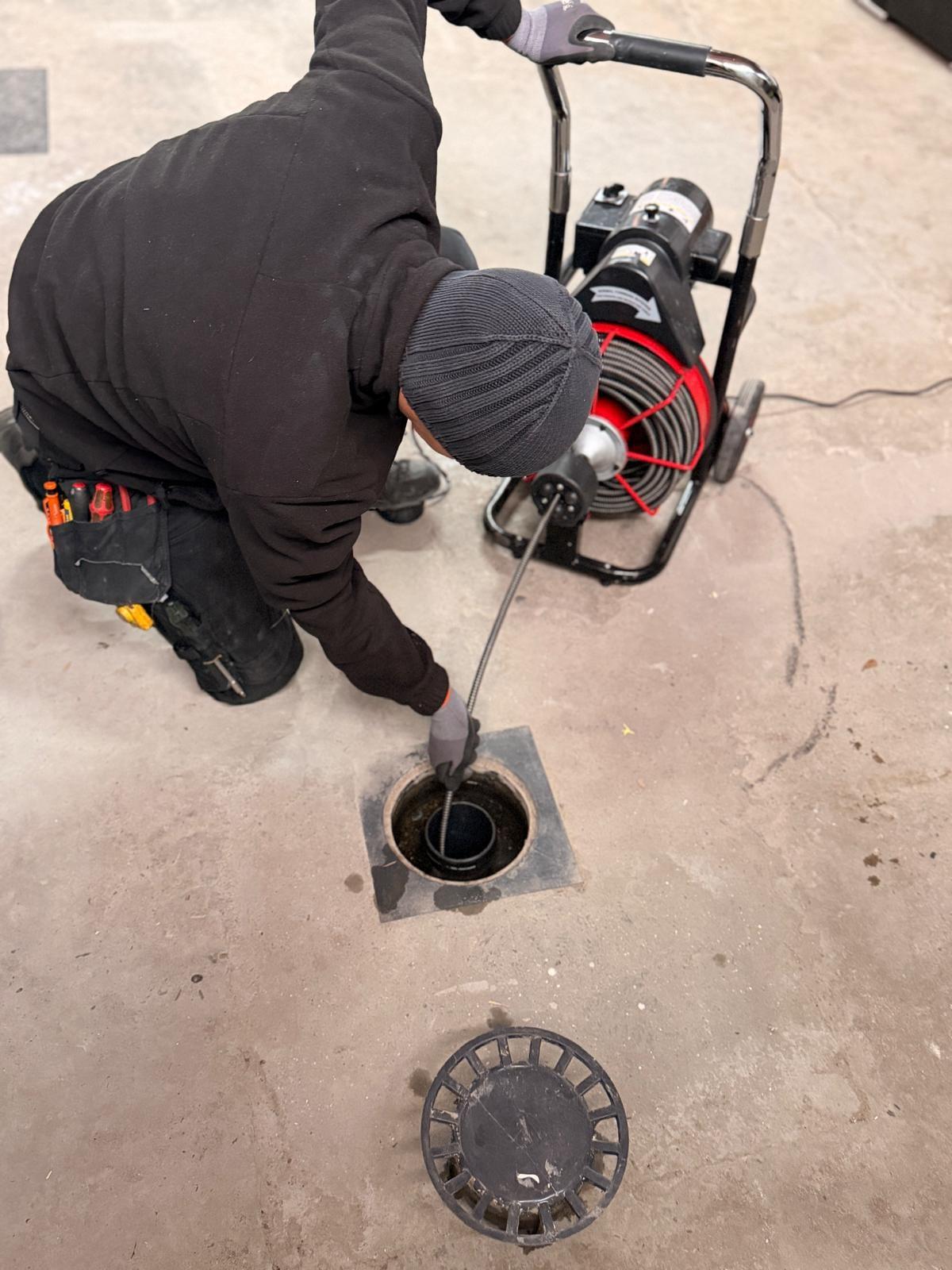 Plombier Plumby débouchant une canalisation au furet électrique